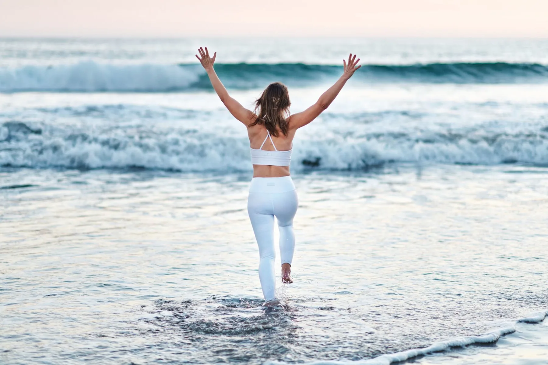 Emma running into the sea with her arms raised