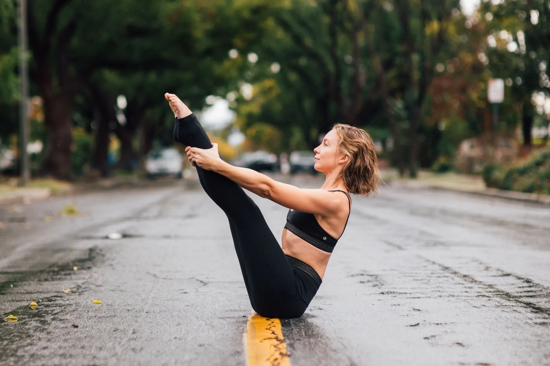 Emma holding a Pilates Teaser in the middle of a tree-lined street
