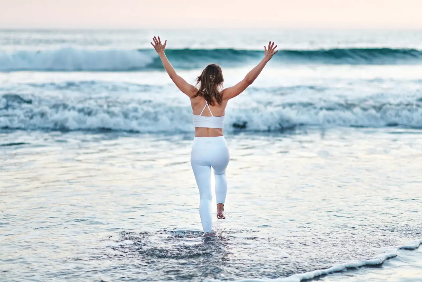 Emma at the beach with her arms in the air
