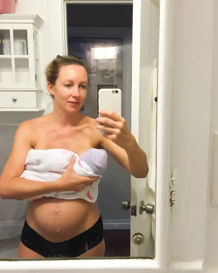 Emma taking a mirror selfie holding her newborn daughter, just after giving birth