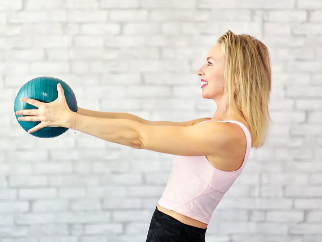 Emma holding a small ball out in front of her with straight arms