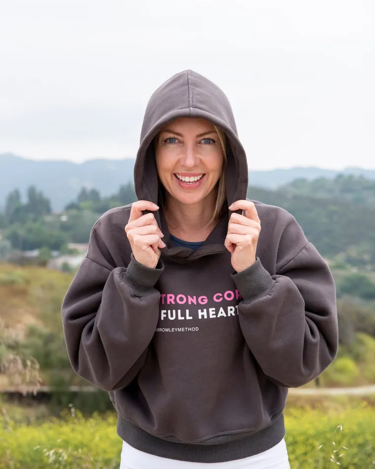 Emma smiling outdoors in a hooded Bromley Method sweatshirt